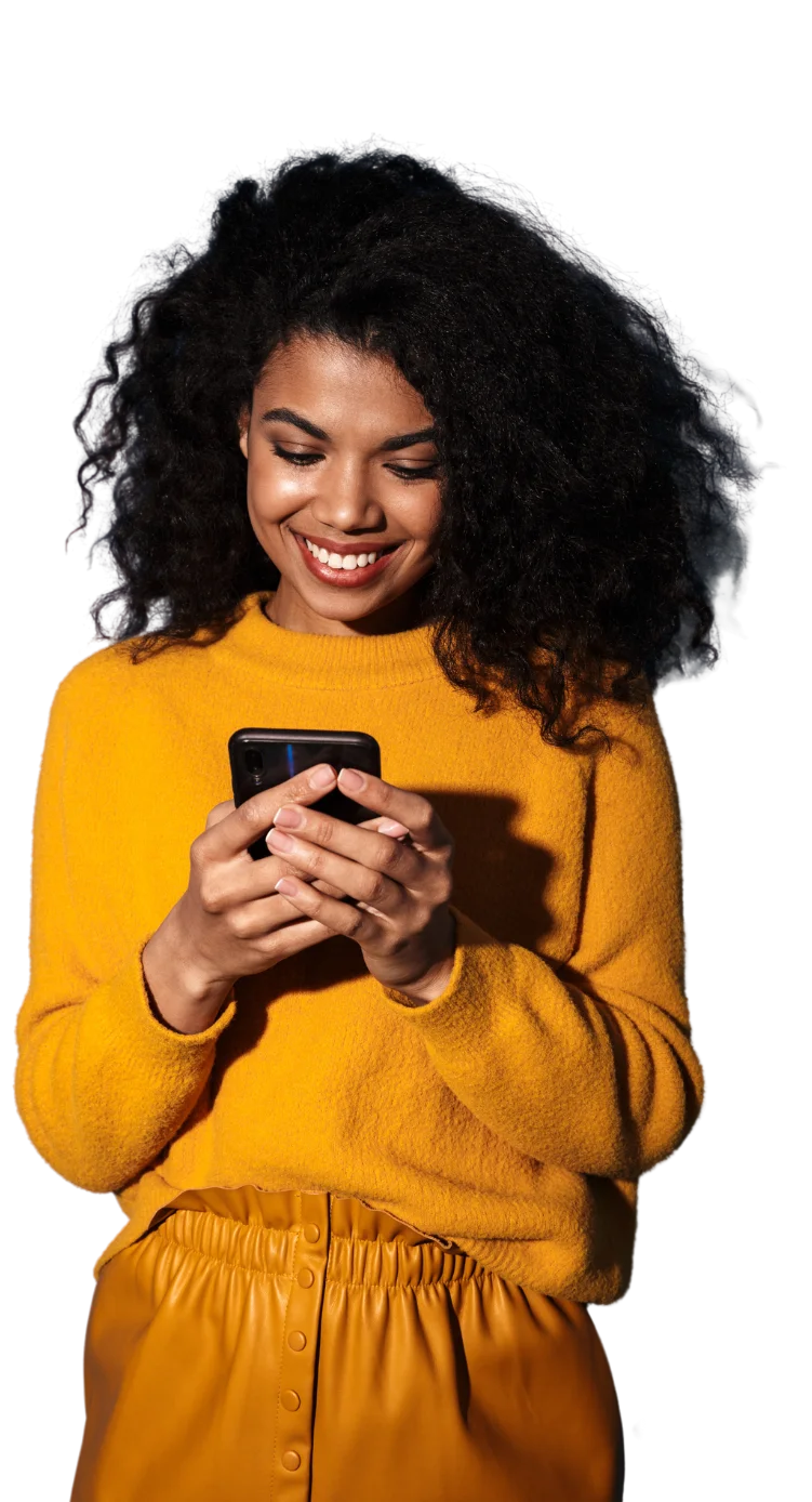 A young woman smiling while using her cell phone.